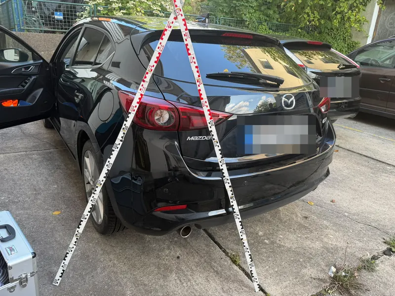 Mazda 3 mit kaum sichtbarem Schaden am hinteren Stoßfänger, Kennzeichen unkenntlich gemacht. Das Kfz-Gutachten ergab 2.000 € Schaden.